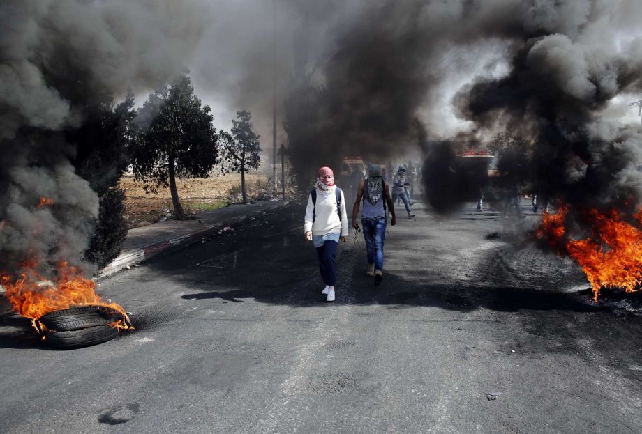 Palestinians burn tires during clashes with Israeli troops near Ramallah West Bank Friday Oct. 16 2015. Tensions and violence have been mounting in recent weeks in part fueled by Palestinian fears that Israel is trying to expand its presence at a maj