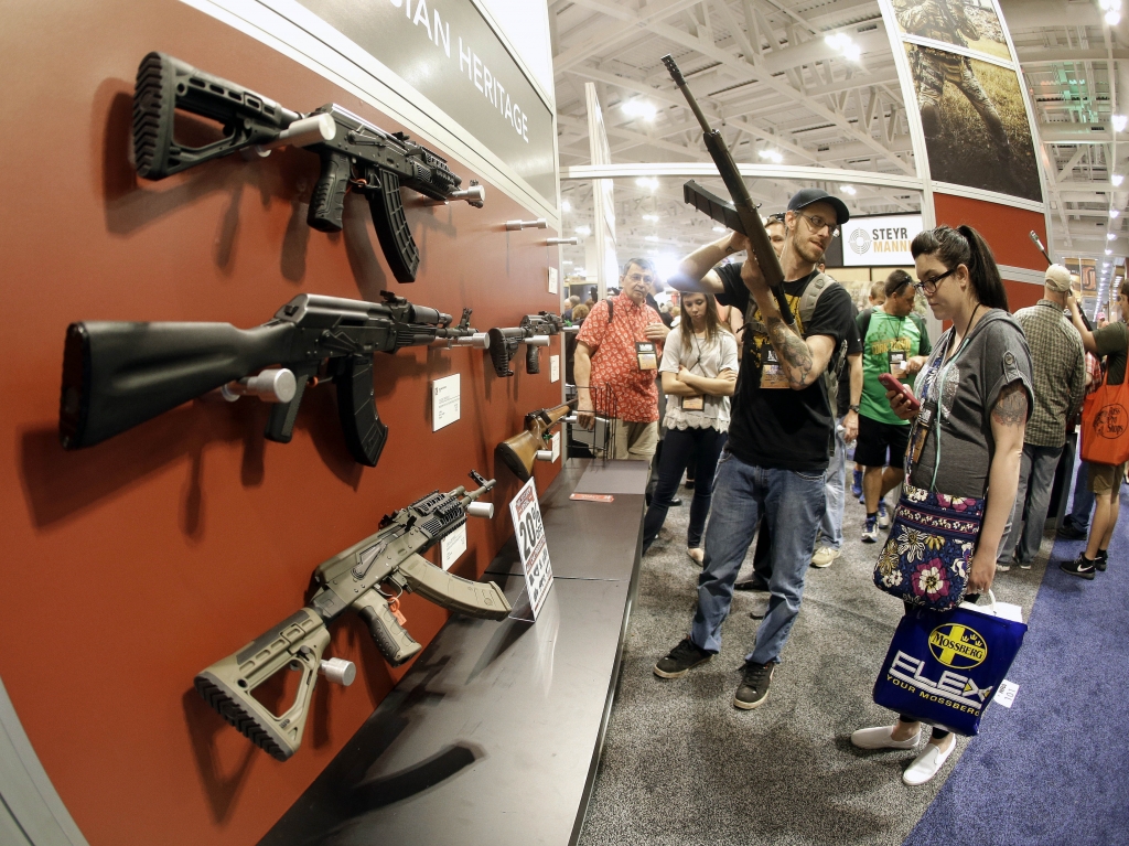 People examine rifles on display at the annual National Rifle Association convention in Nashville Tenn. in April.    Mark Humphrey    
  AP
