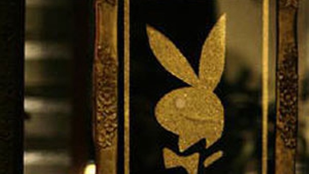 A woman stands behind a Playboy symbol at the entrance during a news launch of the Playboy magazine in a hotel in Manila