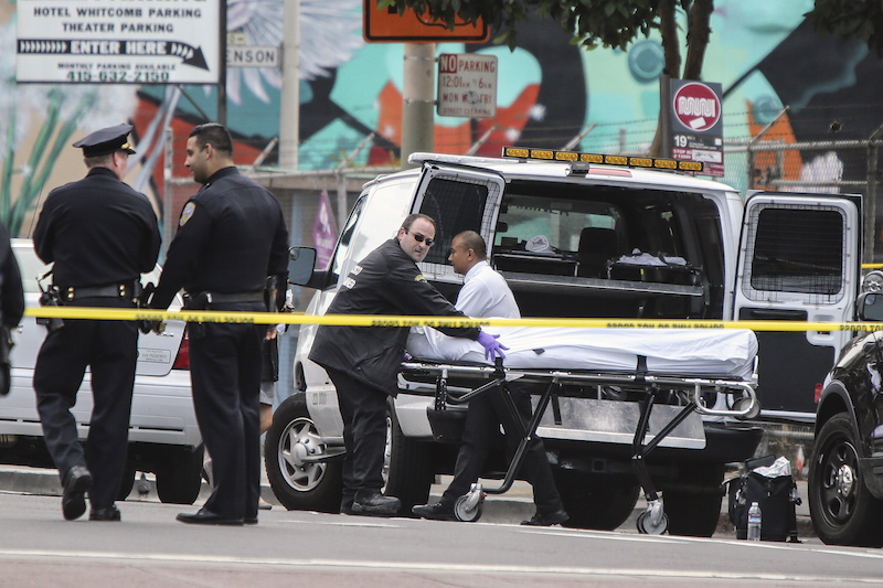 A San Francisco Medical Examiner's employee wheels a body to the van after a San Francisco police sergeant shot and killed a male suspect who allegedly tried to grab a gun from another officer near 8th and Market streets Thursday