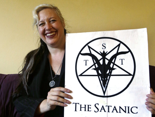 Lilith Starr chapter head of The Satanic Temple of Seattle holds her organization's poster on Wednesday Oct. 28 2015 in Seattle. At the invitation of the Bremerton High School senior class president Starr says that her group of self-described Satan