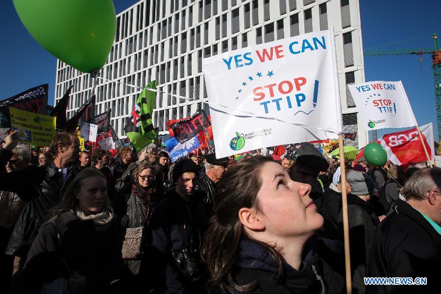 People hold flags and balloons and shout slogans during a protest in Berlin Germany on Oct. 10 2015. Thousands of people protested in Berlin on Saturday against a free trade deal under negotiations between the United States and the European Union