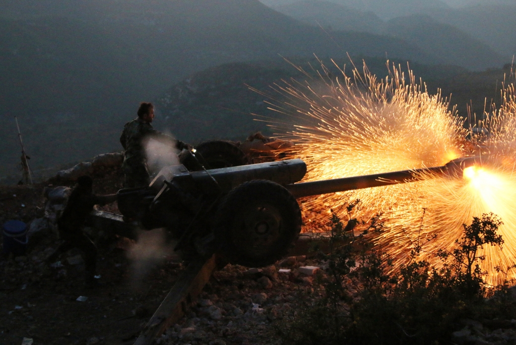 Syrian army personnel fire a cannon in Latakia province close to the Turkish border in Syria