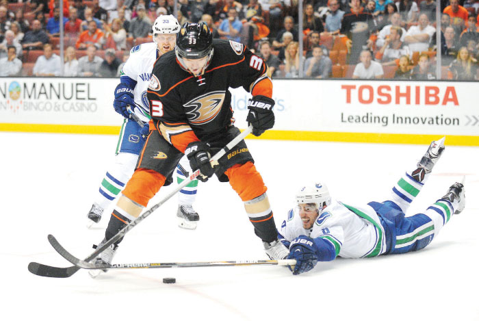 Vancouver Canucks’ center Henrik Sedin and defenseman Chris Tanev defend against Anaheim Ducks’ left-wing Jakob Silfverberg during the overtime period at Honda Center Monday. — Reuters