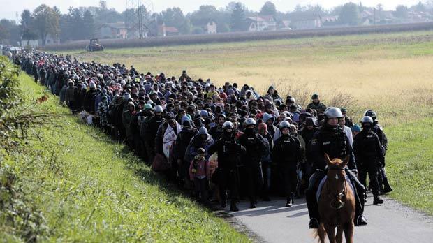 A mounted policeman leads a group of migrants near Dobova Slovenia yesterday. Slovenia’s parliament is expected to approve changes to its laws to enable the army to help police guard the border as thousands of migrants flooded into the country from C