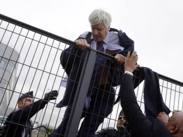 Director of Air France in Orly Pierre Plissonnier nearly shirtless tries to cross a fence after several hundred employees invaded the offices of Air France in Roissy-en-France