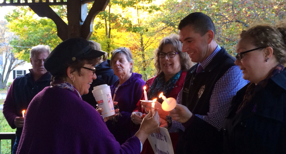 Kathleen Dumont left of Kennebec Valley Behavioral Health lights a candle for Somerset County Sheriff’s Office investigator Mike Pike and others at a vigil Wednesday