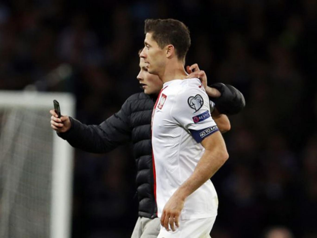 The young fan invades the pitch to take a selfie with Poland striker Robert Lewandowski