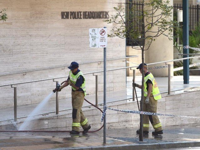 A fireman hoses down the scene where a 15-year-old gunman shot dead a civilian police employee the previous day before being himself gunned down by police in Sydney