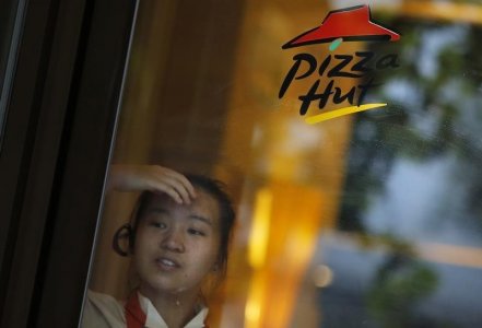 A Pizza Hut employee waits for customers at the entrance of a store in downtown Shanghai