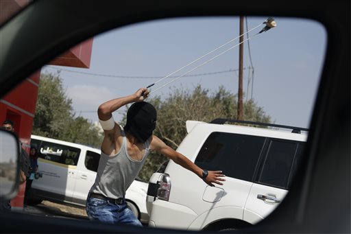 AP10ThingsToSee- A Palestinian uses a slingshot during clashes following a demonstration in the West Bank city of Ramallah Monday Oct. 5 2015. Two Palestinian youths were killed in clashes with Israeli soldiers in the West Bank on Monday as fears spre