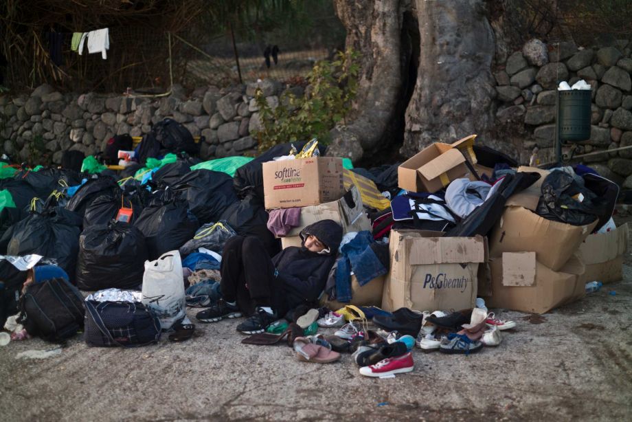 A Syrian refugee boy sleeps on a roadside amid donated clothes and shoes after he and his family arrived on a dinghy from the Turkish coast to the northeastern Greek island of Lesbos Monday Oct. 5, 2015
