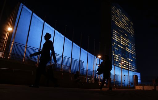 Pedestrians walk by United Nations Headquarters lit up in blue light a day in advance of the 70th Anniversary of the U.N. Friday Oct. 23 2015 in New York. Around 200 other buildings and structures in 60 other countries were also lit in blue to comme