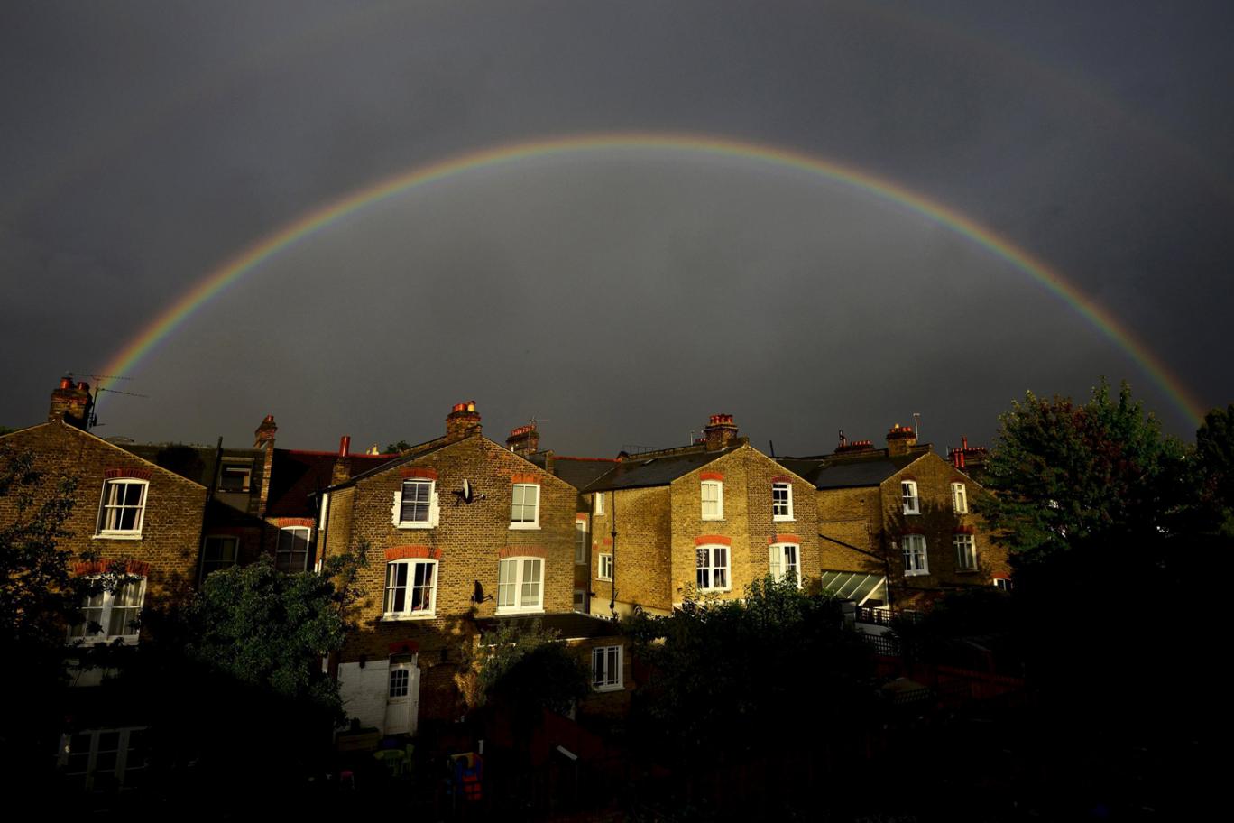 A double rainbow is seen above a row of terrace houses in Clapham south London Britain