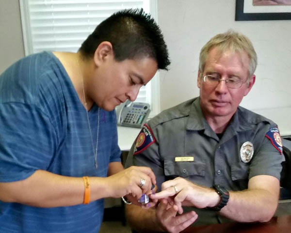 Annette Minjarez education and prevention coordinator at the Family Crisis Center of the Big Bend paints Johnnie Holbrooks’s ring fingernail purple in honor of Domestic Violence Awareness Week