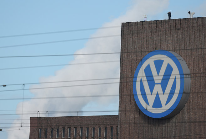 A man looks through binoculars as he stands next to a corporate logo of Volkswagen on the rooftop of the former power plant of the German car manufacturer inÂ Wolfsburg Germany Friday Sept. 25 2015. Volkswagen's supervisory board is meeting Friday