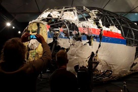 Journalists take images of part of the reconstructed forward section of the fuselage after the presentation of the Dutch Safety Board's final report into what caused Malaysia Airlines Flight 17 to break up high over Eastern Ukraine last year killing all