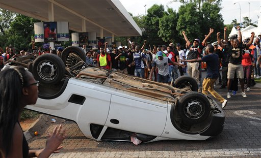 Students from the University of the Witwatersrand overturn a vehicle off campus after blocking traffic during protests in Johannesburg Monday Oct. 19 2015. Students demonstrating against the increase of tuition fees at some top South African universiti