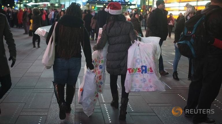 Women make their way though Times Square with bags of purchases from Toys R Us in New York