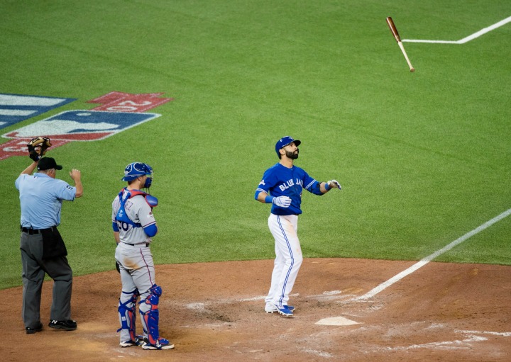 Toronto Blue Jays&#039 Jose Bautista right flips his bat in the air while celebrating a three-run home run in front of Texas Rangers catcher Chris Gimenez during seventh inning game five American League Division Series baseball action in Toronto on Wed