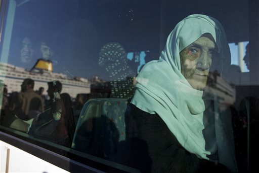 An elderly Syrian woman looks out from a window of a bus after her arrival aboard a ferry from the Greek island of Lesbos at the Athens&#039 port of Piraeus Wednesday Oct. 14 2015. The International Organization for Migration said more than 593,000 peo