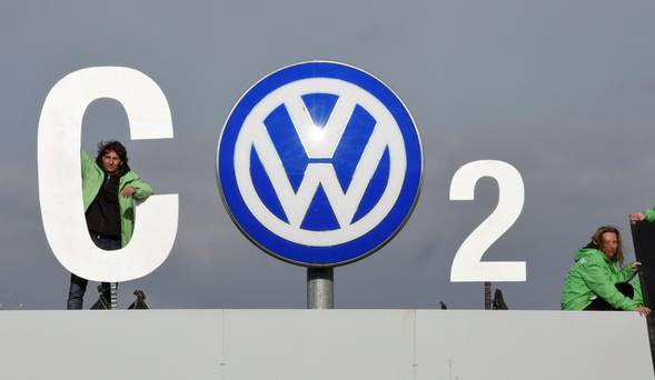 A Greenpeace activist adds a pointed message to a Volkswagen sign at the company's plant in Wolfsburg Germany