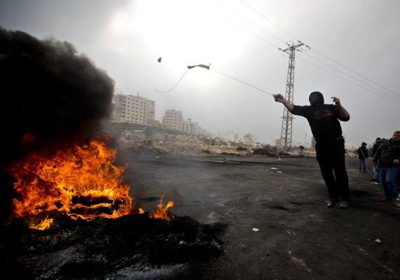 A Palestinian protester hurls stones at Israeli troops