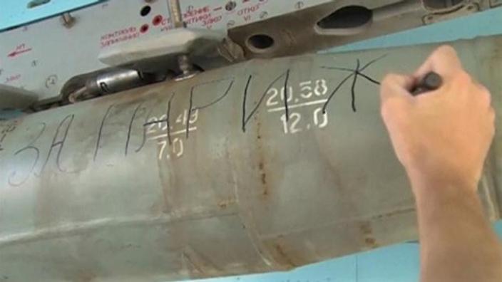 A ground crew member writing the words'For Paris on a bomb on a Russian military jet      
        
            
    
               Sh