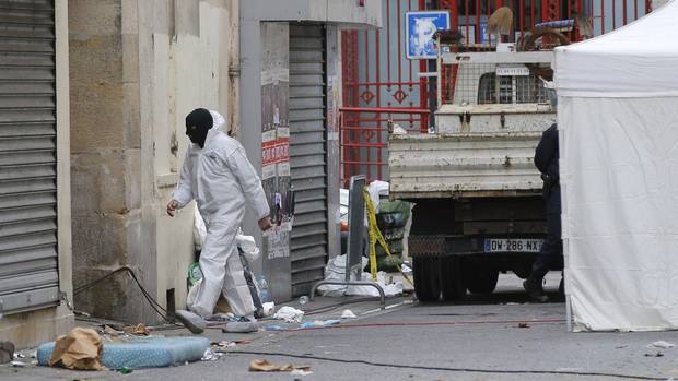 A hooded investigating police officer enters the building of Wednesday's raid on an apartment in Paris suburb Saint Denis