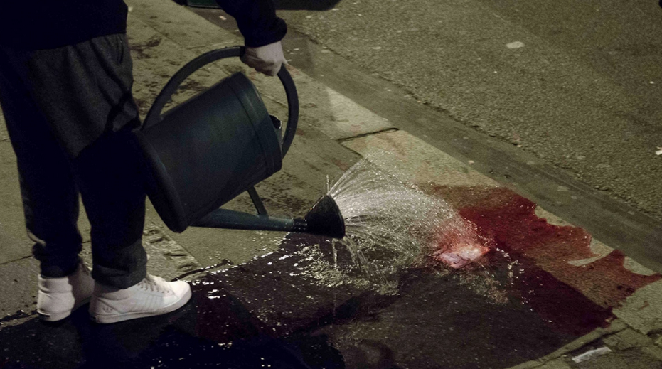 A resident washes away blood from Rue Oberkampf in the 11th district Friday night