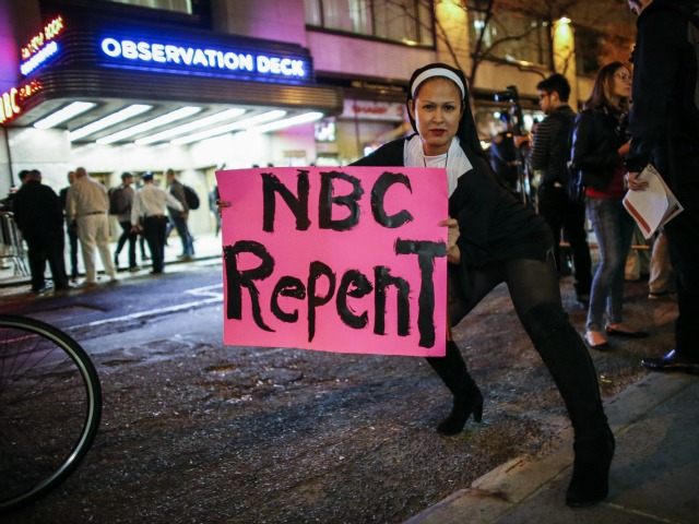 A woman dressed as nun holds a poster as she poses for