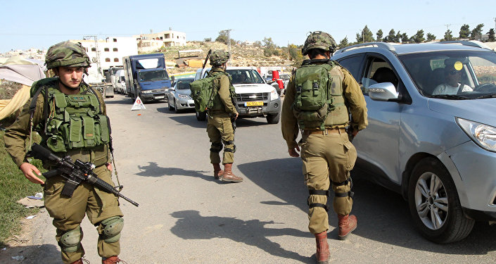 Israeli soldiers man a checkpoint at one of the entrances of the West Bank city of Hebron