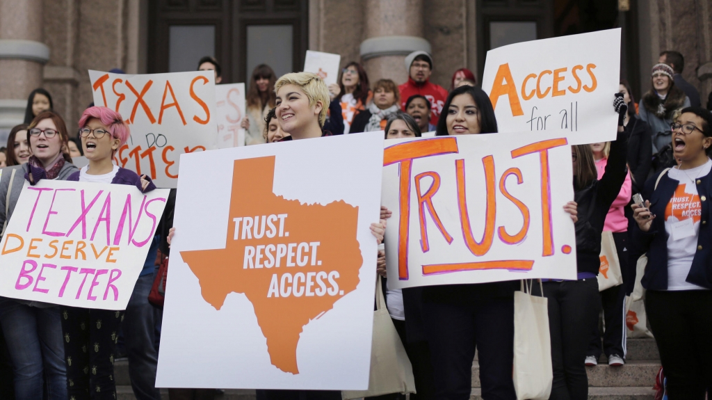 Abortion rights activists hold signs during a rally on the steps of the Texas Capitol in June