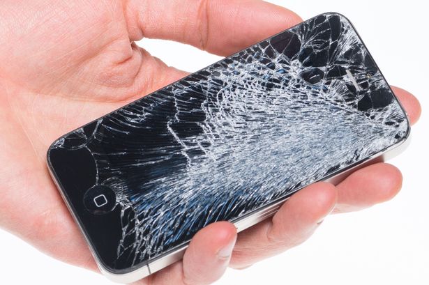 Hand holding Apple iPhone 4 with broken screen