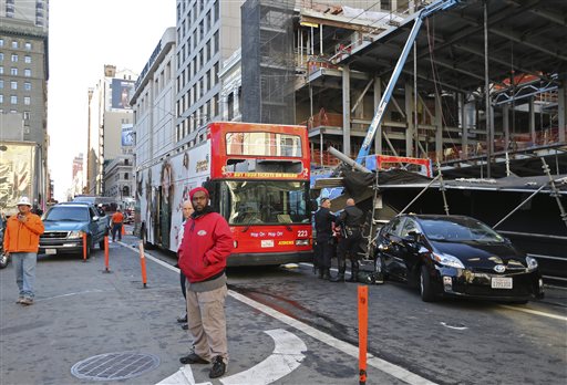 Bystanders look on next to an open-air tour bus at right under scaffolding that crashed into a construction site near Union Square Friday Nov. 13 2015 in San Francisco. Officials say there may have been as many as 30 people aboard the bus. There&#039