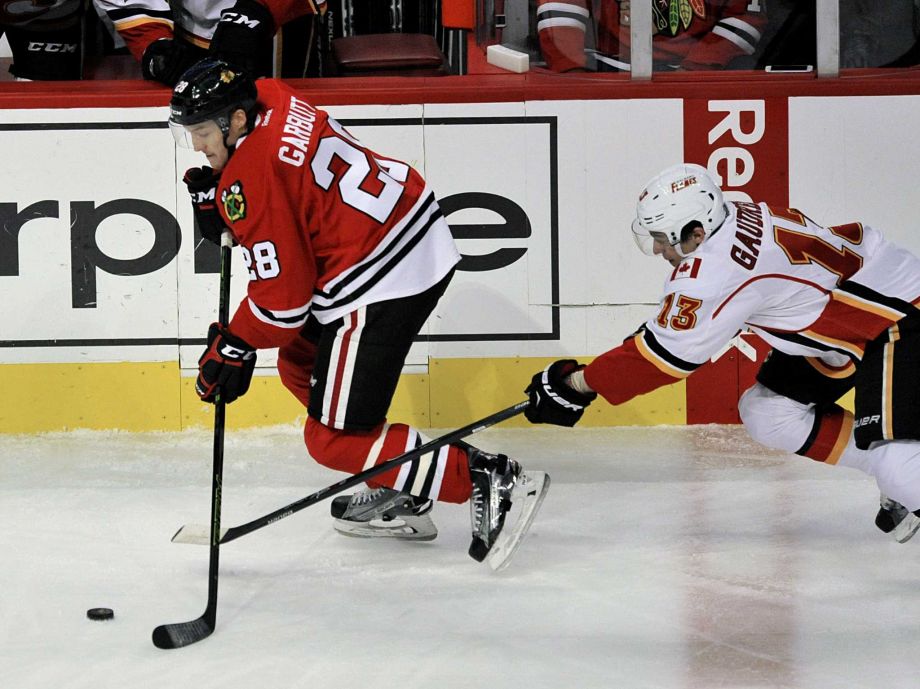 Chicago Blackhawks Ryan Garbutt moves the puck against Calgary Flames Johnny Gaudreau during the first period of an NHL hockey game Sunday Nov. 15 2015 in Chicago