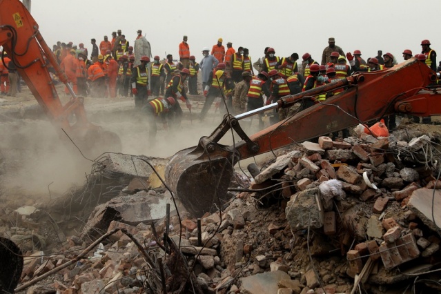 Excavators dig rubble of a collapsed building looking for survivors in Lahore Pakistan Friday