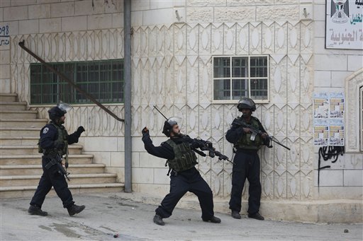 Israeli border policeman throws a tear gas canister during clashes with Palestinian protesters in the West Bank city of Hebron Friday Nov. 6 2015