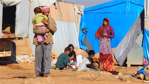 Internally displaced Syrians stand outside tents at a makeshift refugee camp in Sinjar town in Idlib province Syria