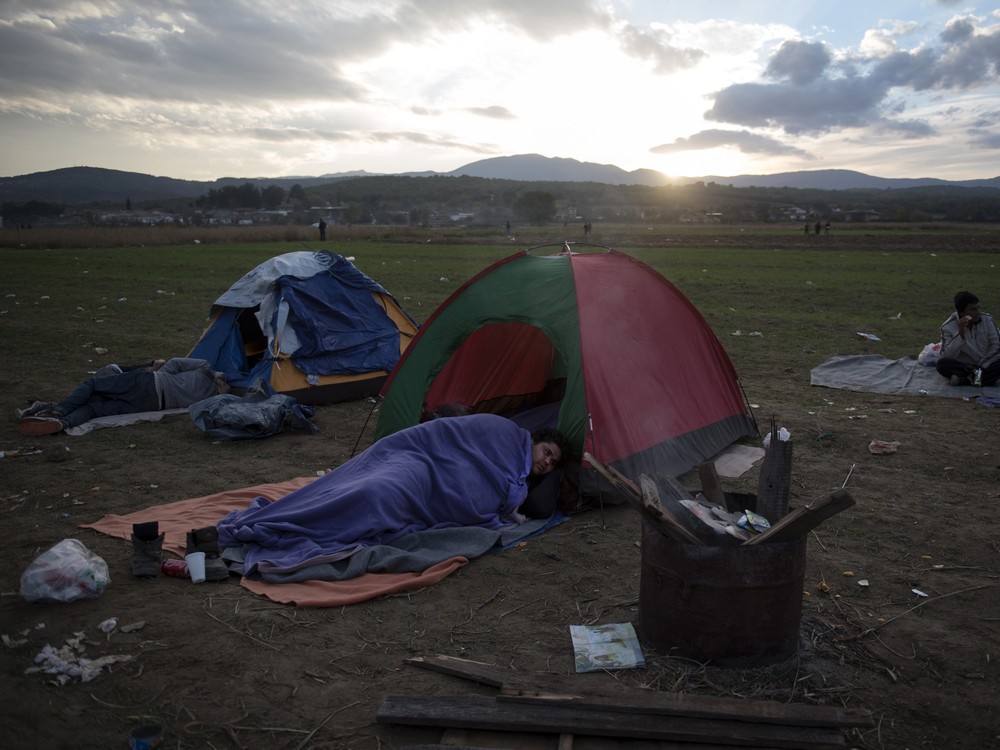 Migrants rest outside their tents as the sun sets near the village of Idomeni at the Greek Macedonian border on Monday Nov. 23 2015