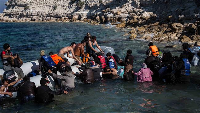 Refugees walk towards a dinghy to travel to the Greek island of Chios from Cesme in the Turkish province of Izmir