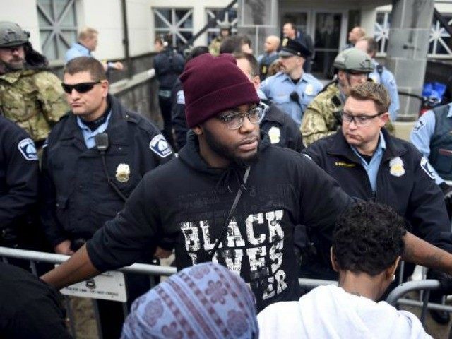 A member of the Black Lives Matter movement tries to keep demonstrators back from the police line in front of a police precinct during a protest in Minneapolis on November 18