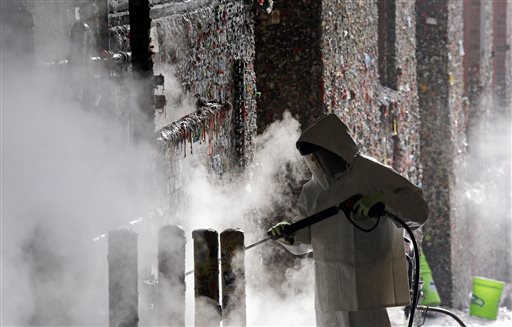 A worker uses a powerful steam cleaner to work decades of gum off a'gum wall that stretches behind and above him Tuesday Nov. 10 2015 in Seattle. Tourists and locals have been sticking their used chewing gum to the wall near Pike Place Market for 20