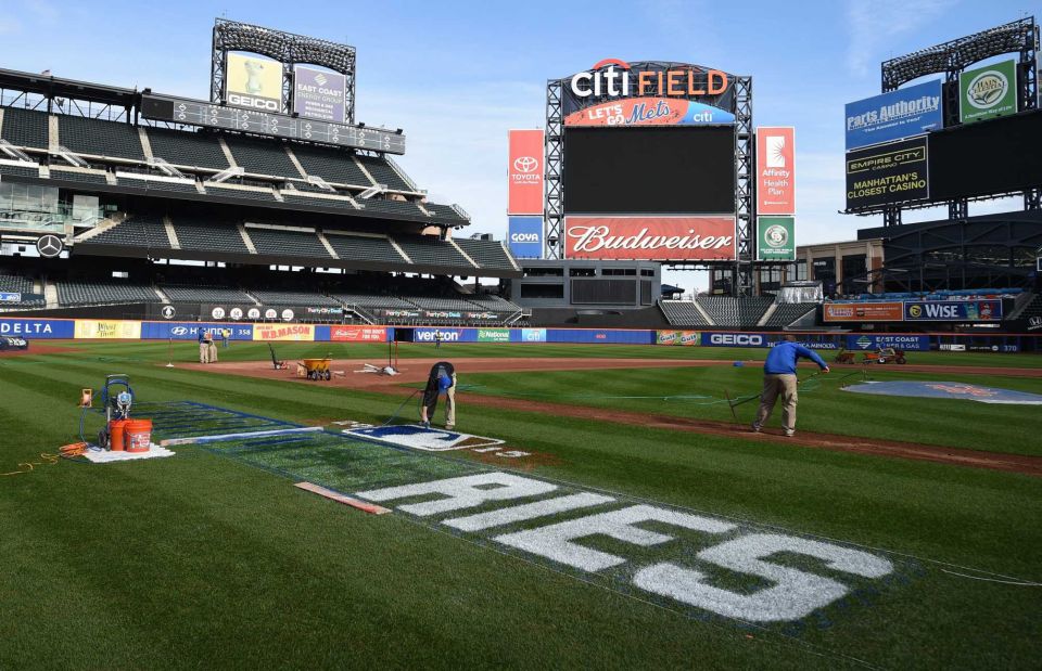 Members of the grounds crew rake the field