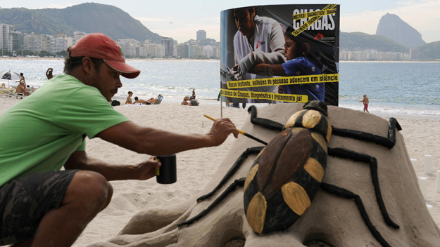 A beach artist gives the final touches to a sand sculpture of the Chagas disease's vector the 'assassin bug&#039  during a demonstrati