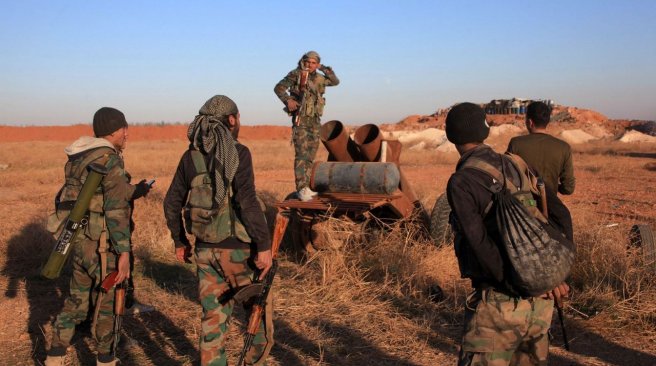 A group of Syrian pro-government forces inspect a home-made rocket launcher during a military operation against the Islamic State Jihadist Group