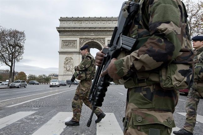 French soldiers cross the Champs Elysees avenue passing the Arc de Triomphe in Paris Monday Nov. 16 2015. While few in the war-weary West want to send ground troops to the areas controlled by Islamic State it may actually be even harder to find anyone