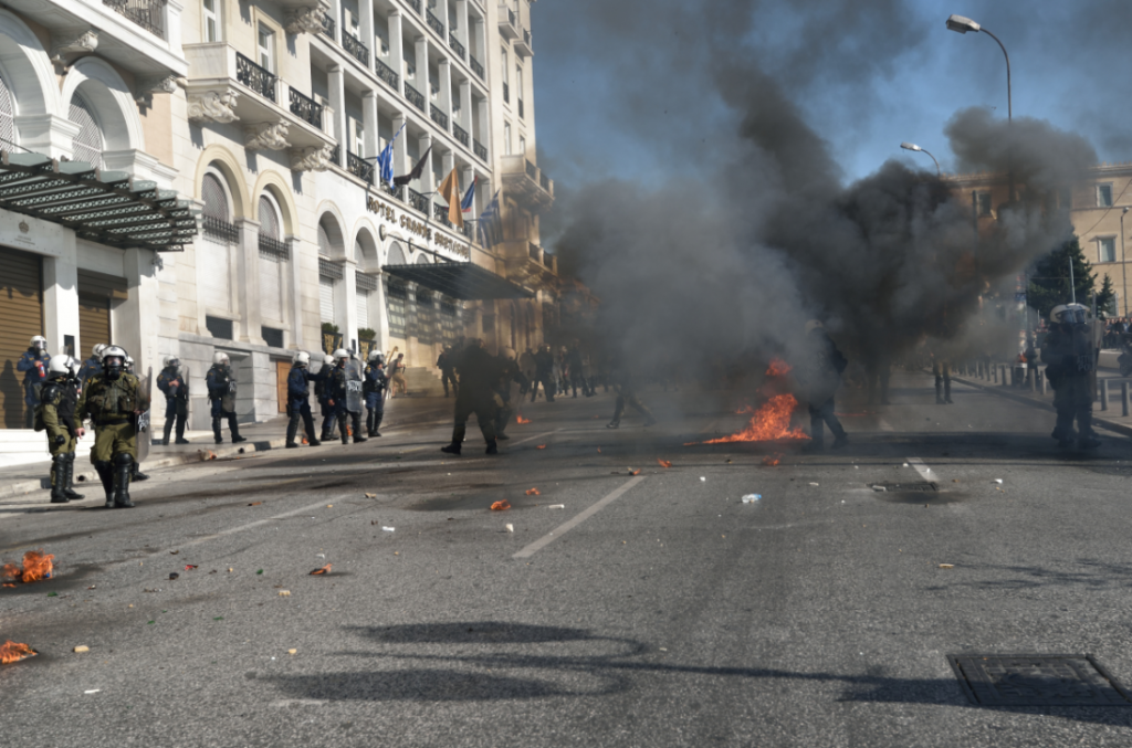 Clashes break out between a group of youths and riot police while thousands march against tax rises and pension reforms in Athens