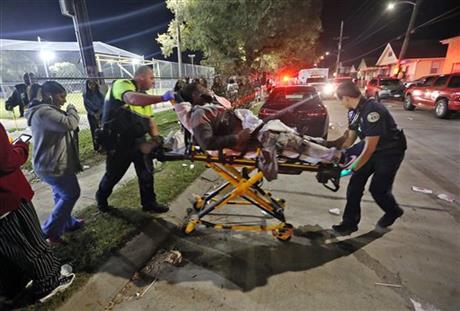 Officials remove a man from the scene following a shooting in New Orleans&#039 9th Ward on Sunday Nov. 22 2015. Police spokesman Tyler Gamble says police were on their way to break up a big crowd when gunfire erupted at Bunny Friend Park. (Michael DeMo