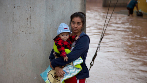 A woman holds her baby in a flooded street as she waits to be taken to a shelter in Guadalajara Mexico